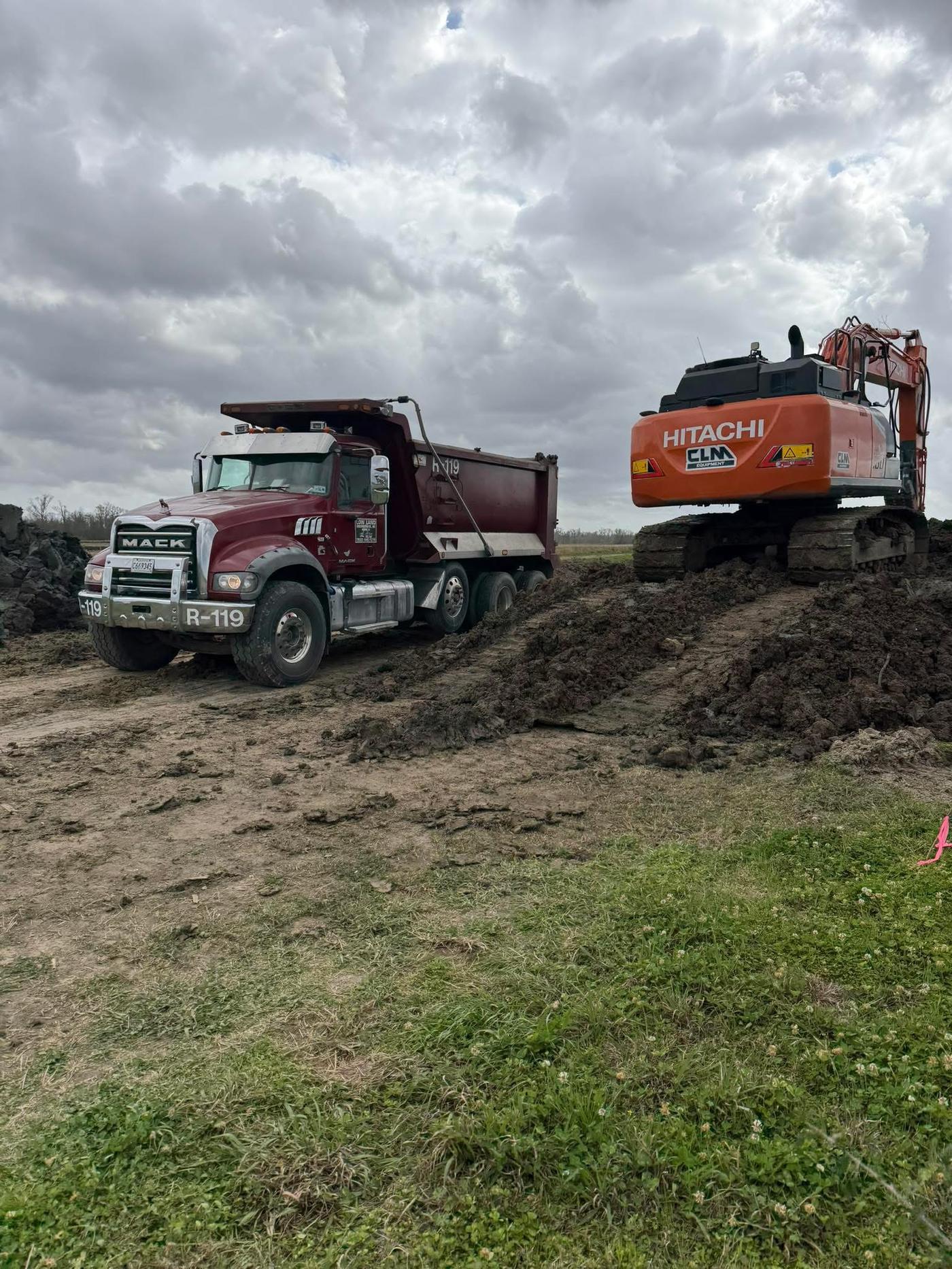 Dump truck and excavator staged on a muddy South Louisiana job site