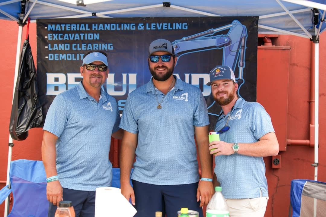 The Beauland Industries team standing in front of a company banner listing their site work and excavation services